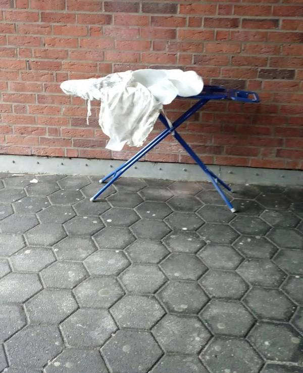 Ein Bügelbrett steht an einer Mauer.