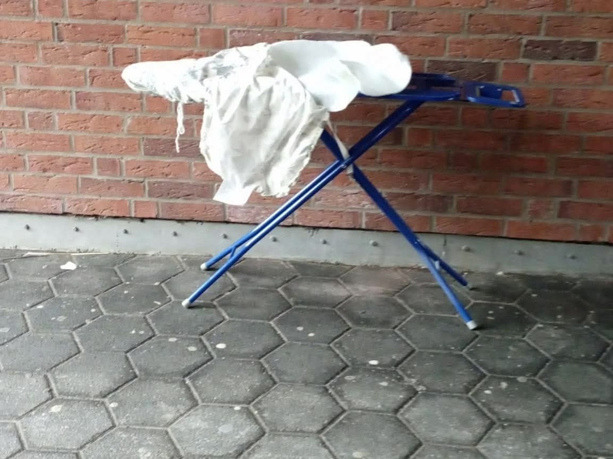 Ein Bügelbrett steht an einer Mauer.