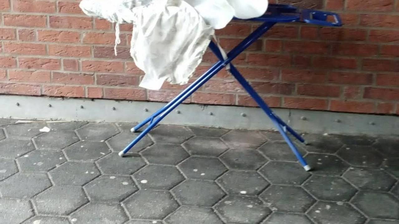 Ein Bügelbrett steht an einer Mauer.