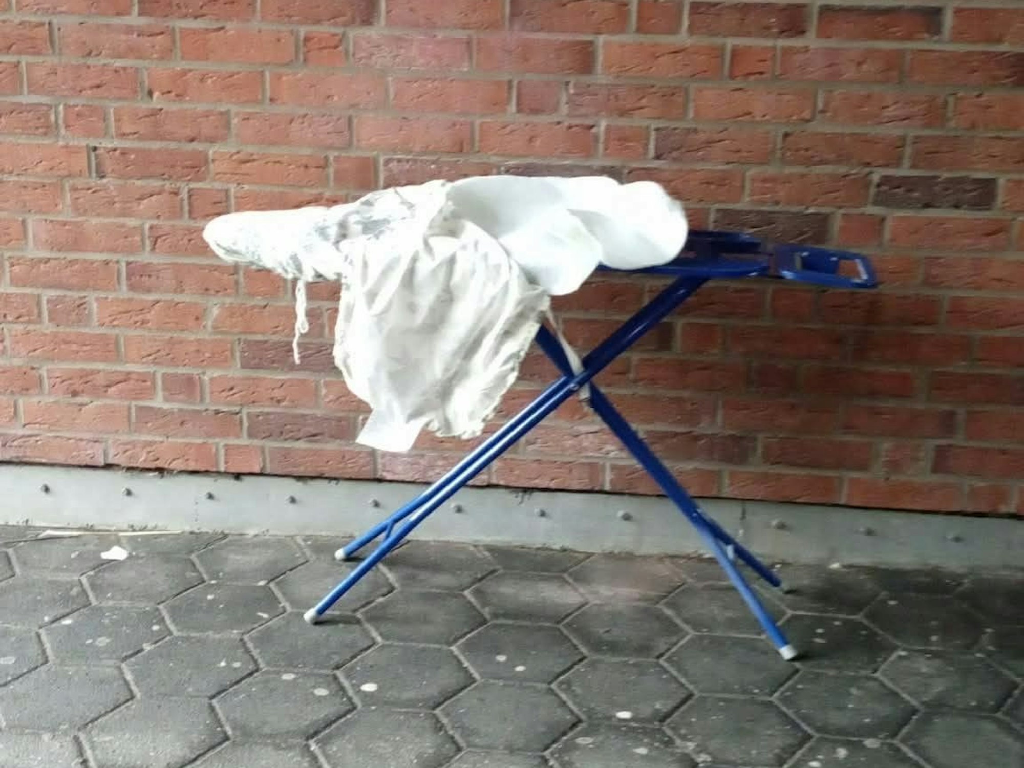 Ein Bügelbrett steht an einer Mauer.