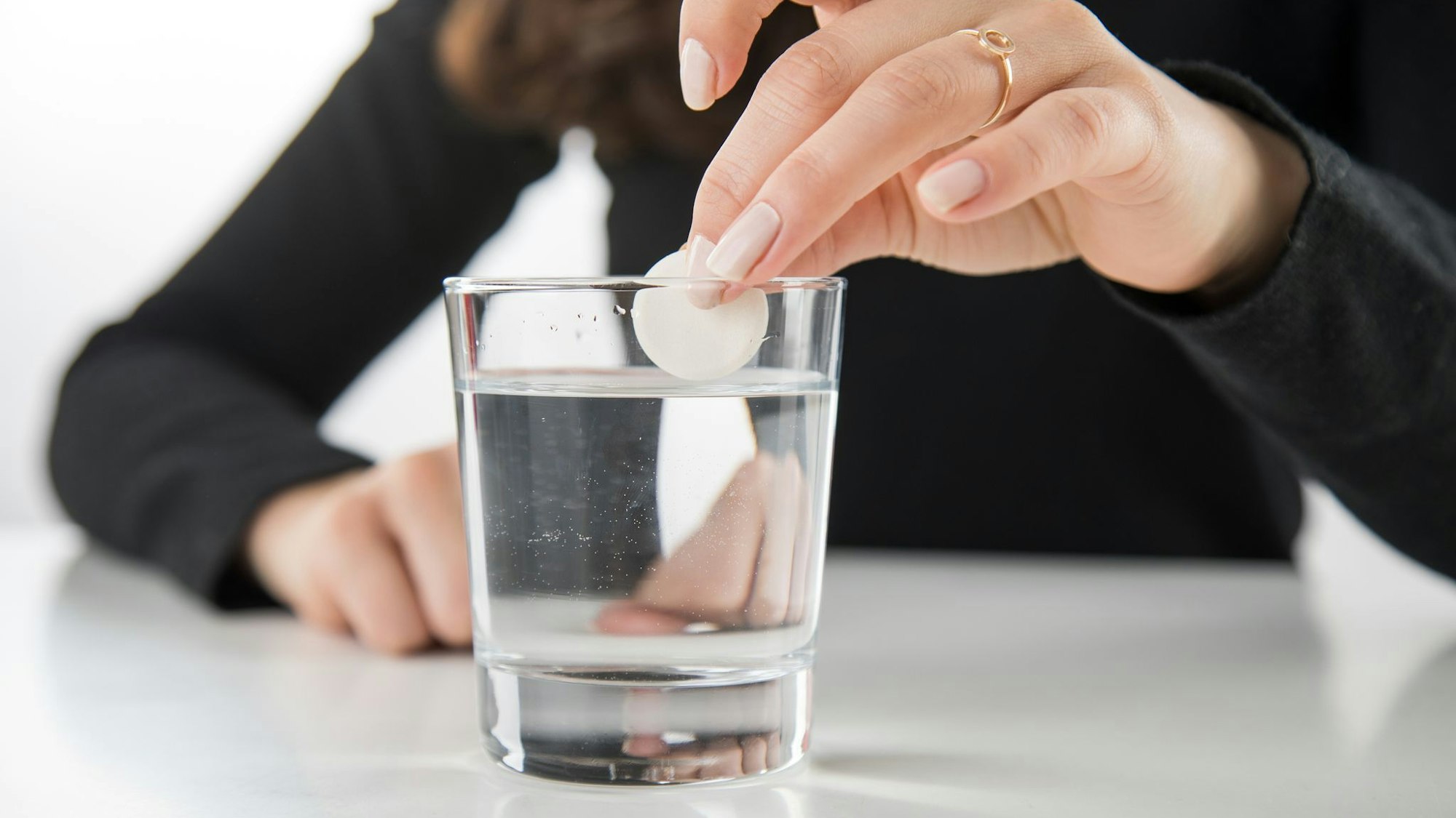 Brausetablette wird in ein Glas Wasser gegeben