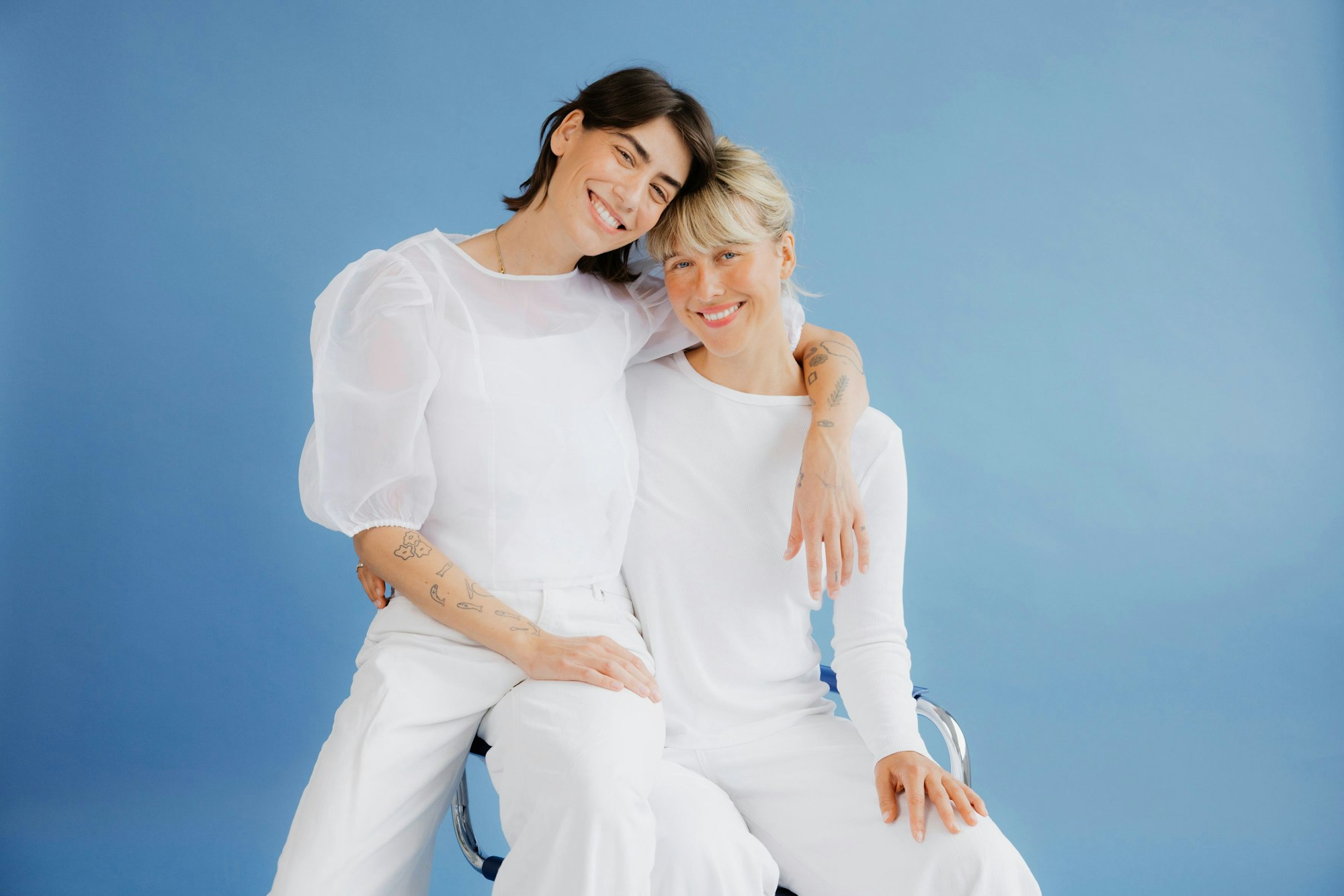 Zwei Frauen umarmen sich, beide sind ganz in Weiß gekleidet.