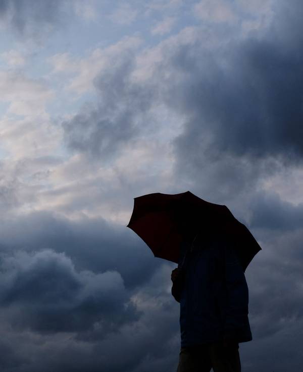 Regen und Wolken. Mann mit Schirm.
