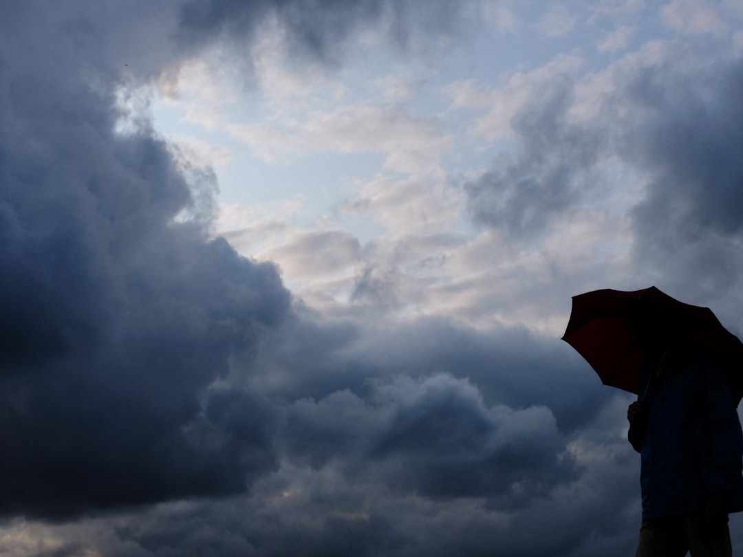 Regen und Wolken. Mann mit Schirm.