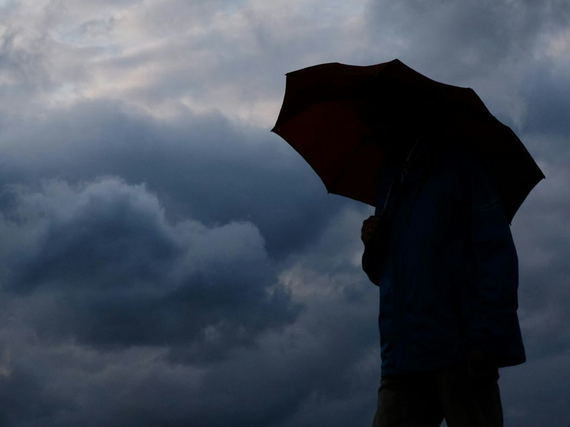 Regen und Wolken. Mann mit Schirm.