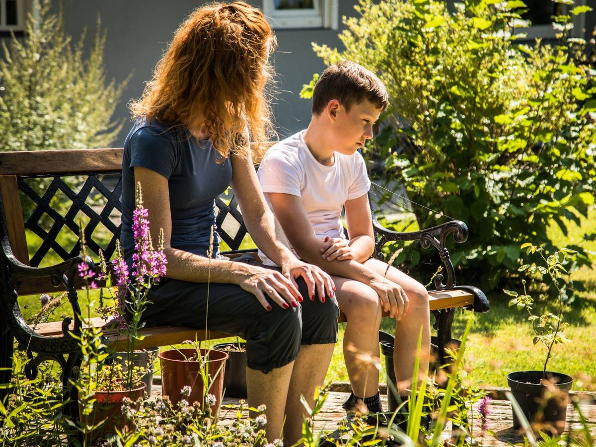 Mutter spricht mit ihrem Sohn auf einer Gartenbank