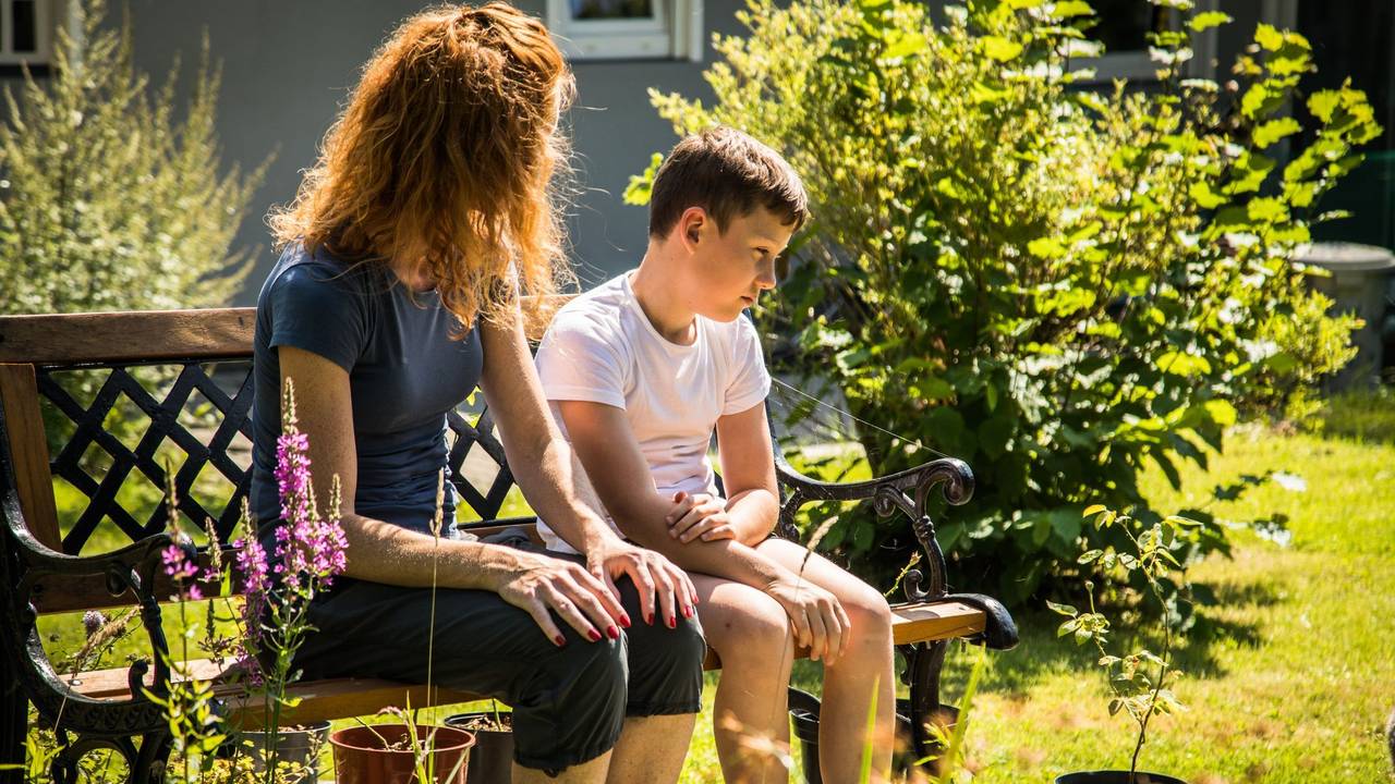 Mutter spricht mit ihrem Sohn auf einer Gartenbank