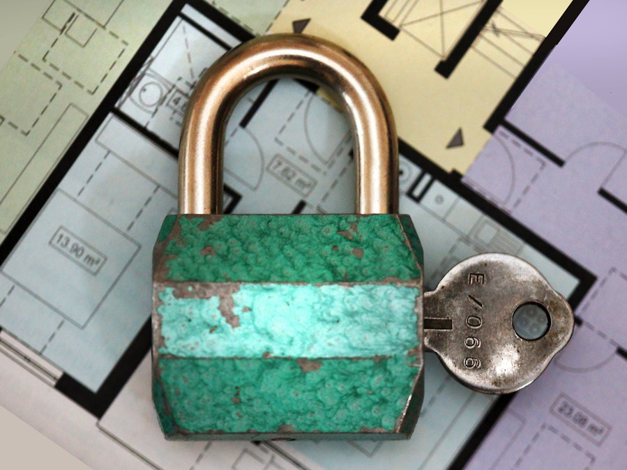 Vorhängeschloss und Schlüssel auf Bauplänen