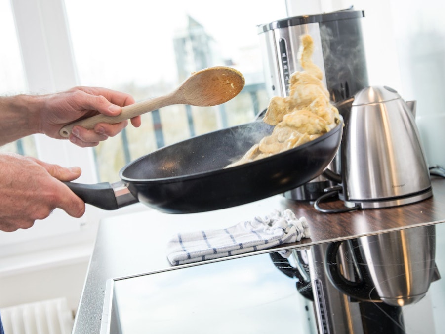 Mann brät Fleisch in einer Pfanne