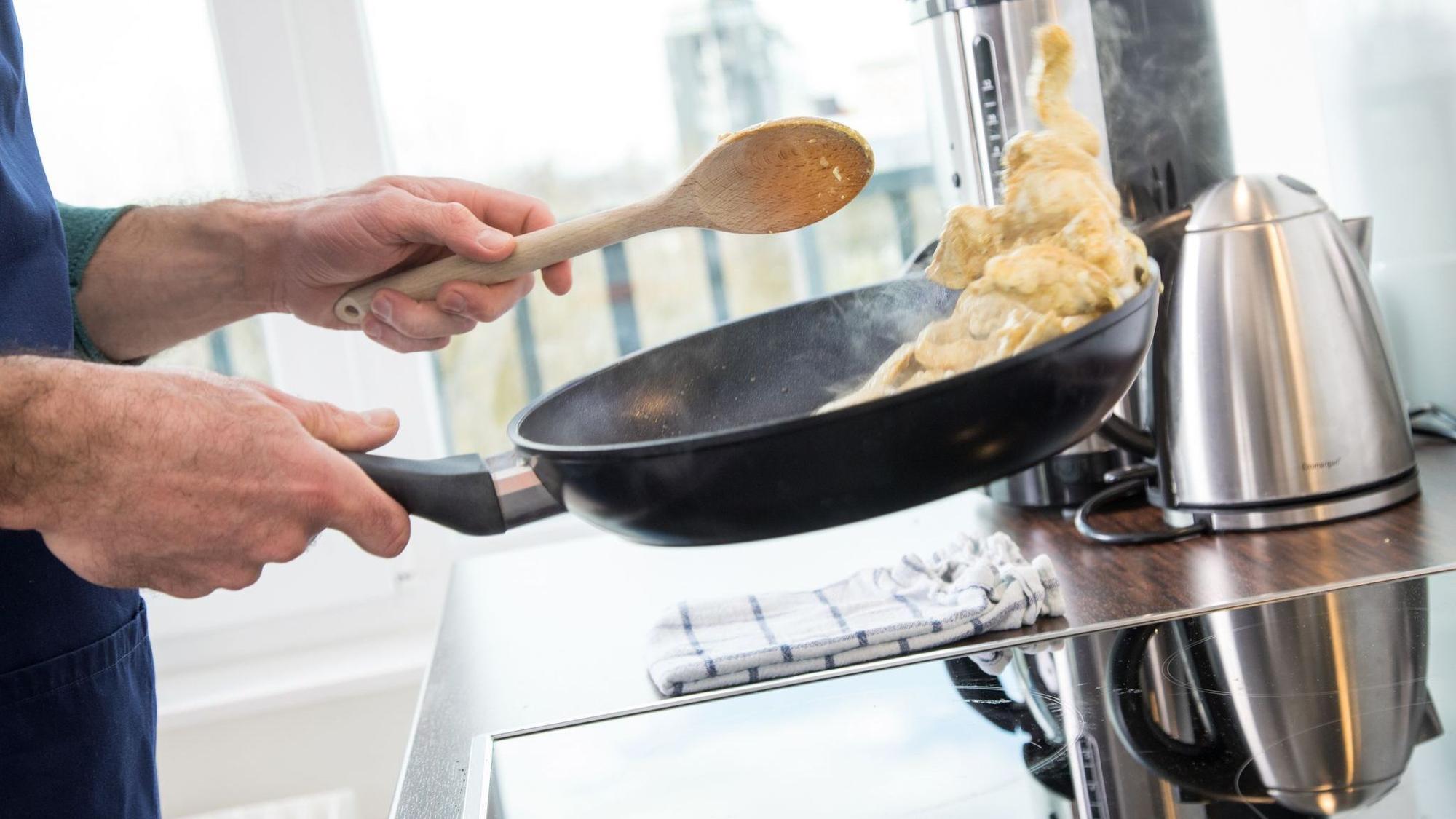 Mann brät Fleisch in einer Pfanne