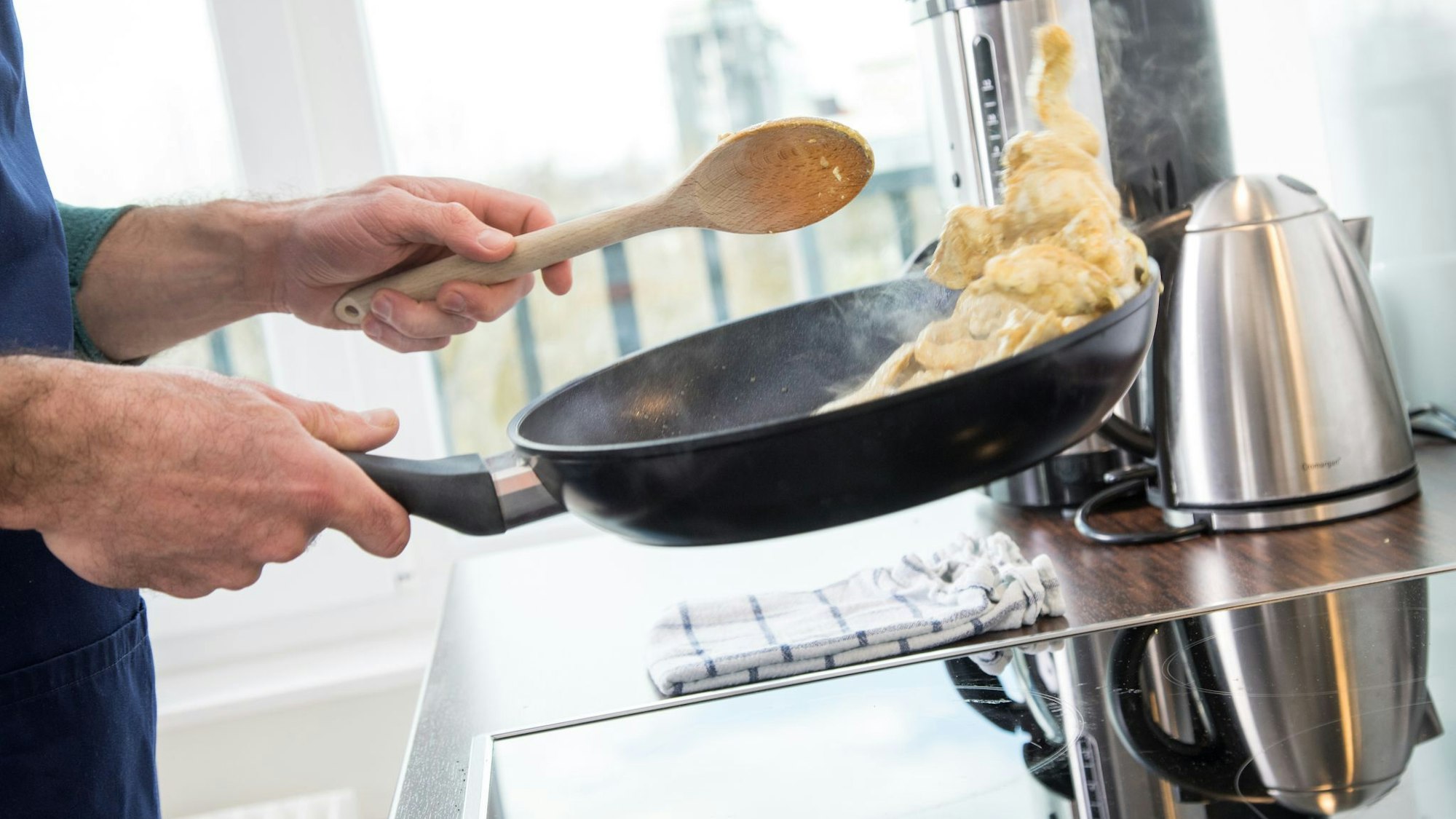 Mann brät Fleisch in einer Pfanne