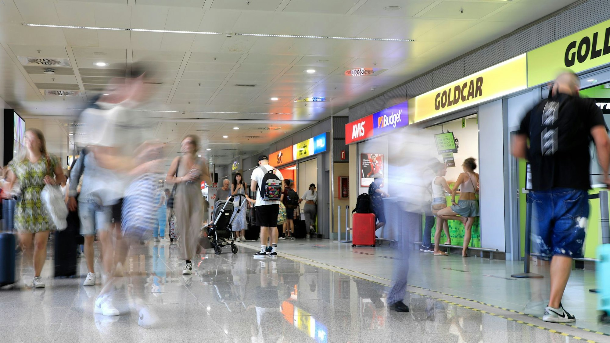 Menschen gehen an Mietwagen-Firmen vorbei