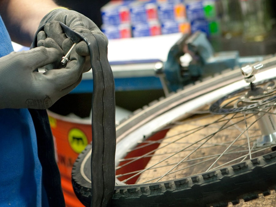 Mitarbeiter einer Fahrradwerkstatt prüft einen Fahrradschlauch