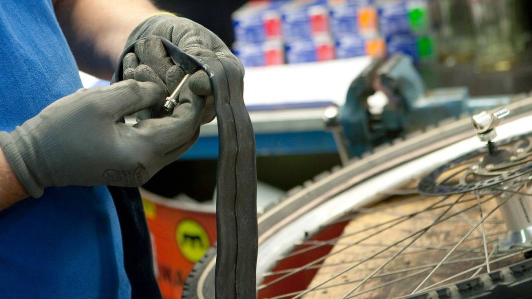 Mitarbeiter einer Fahrradwerkstatt prüft einen Fahrradschlauch