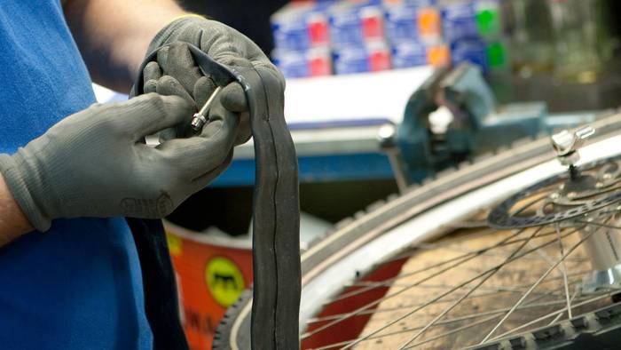 Mitarbeiter einer Fahrradwerkstatt prüft einen Fahrradschlauch