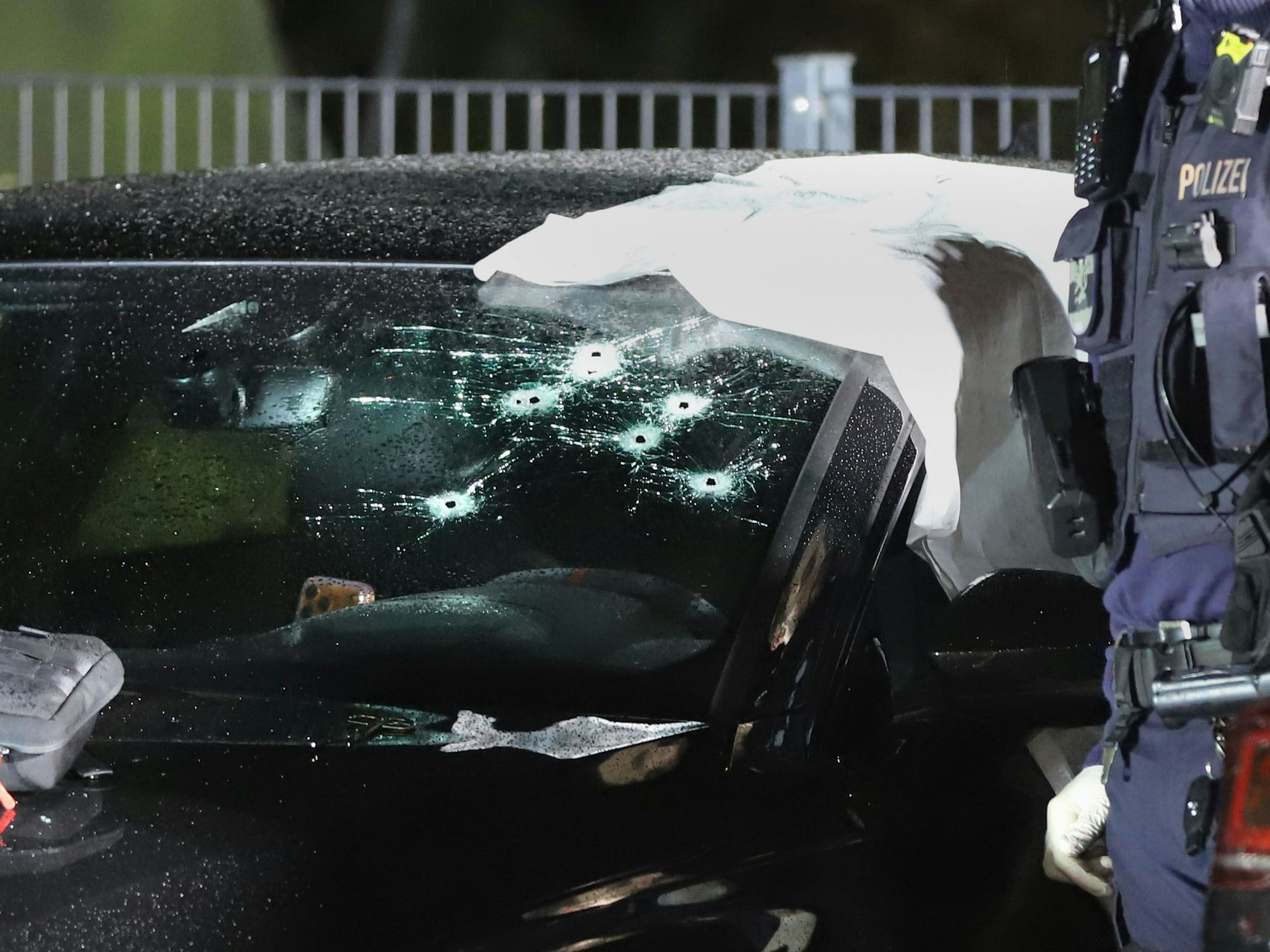 Einsatzkräfte der Polizei an dem durch Schüsse getroffenen Pkw. Ein Mann wurde durch die Windschutzscheibe angeschossen und lebensgefährlich verletzt.