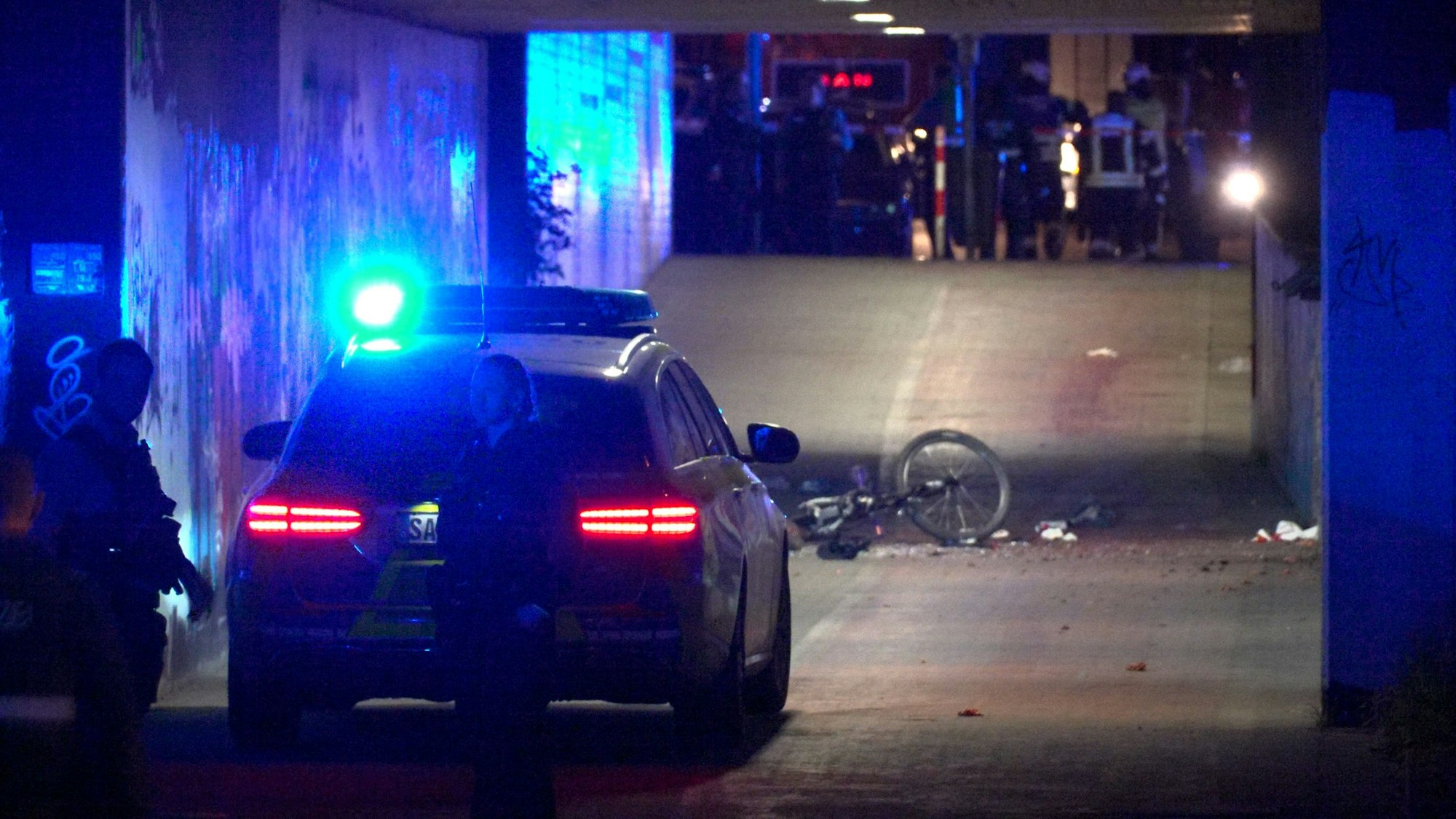 Polizei und Feuerwehr sind an einer Unterführung im Einsatz. Nach einem lauten Knall hat die Polizei unter einer Fußgängerbrücke im Saarland einen Toten und mehrere Schwerverletzte gefunden.