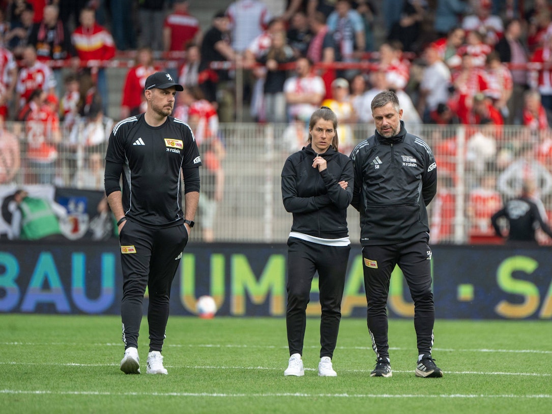 Trainerin Marie-Louise Eta (m.) mit ihren Co-Trainern Andreas Kerwin und Sebastian Bönig schauen nach der Niederlage gegen Wolfsburg frustriert.