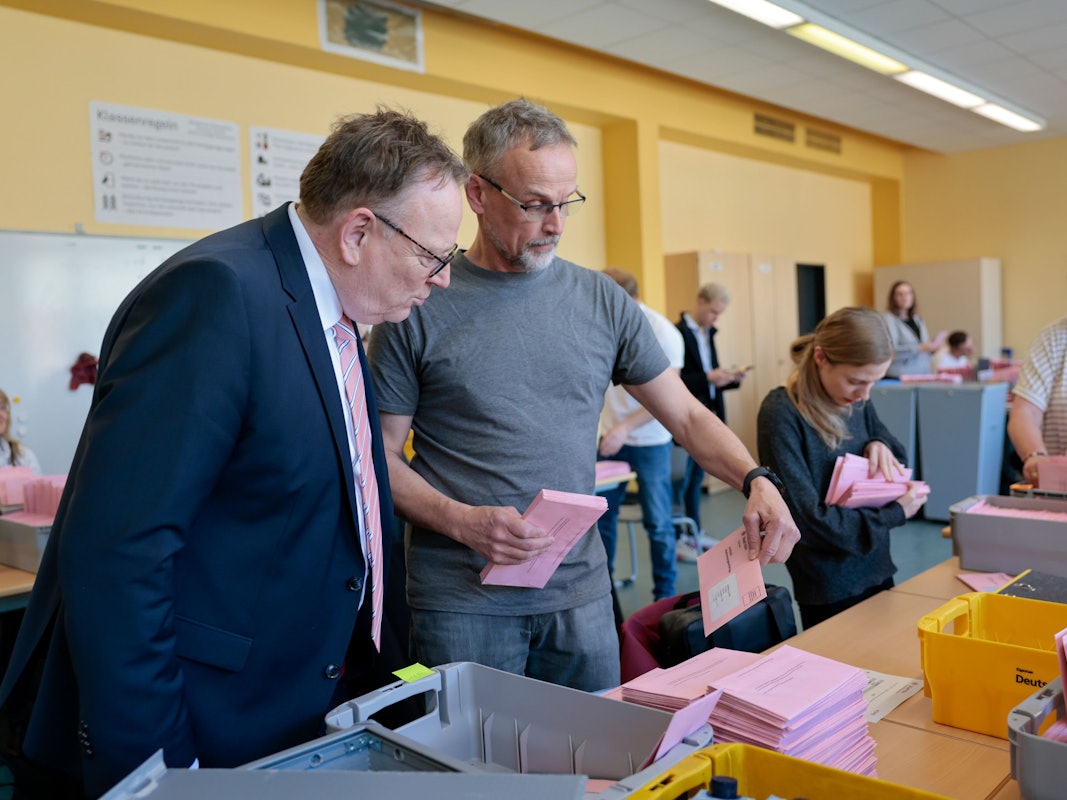 Oberbürgermeister Torsten Burmester besucht das Auszählzentrum und läßt sich von einem Abstimmungshelfer die amtliche Abstimmungsunterlagen der Stadt Köln für die Briefwahl des jeweiligen Bezirks zeigen.