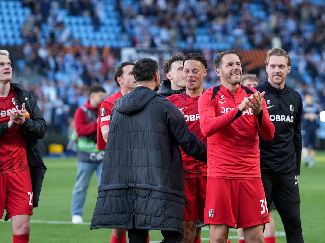 Profis des SC Freiburg feiern vor der Fankurve.