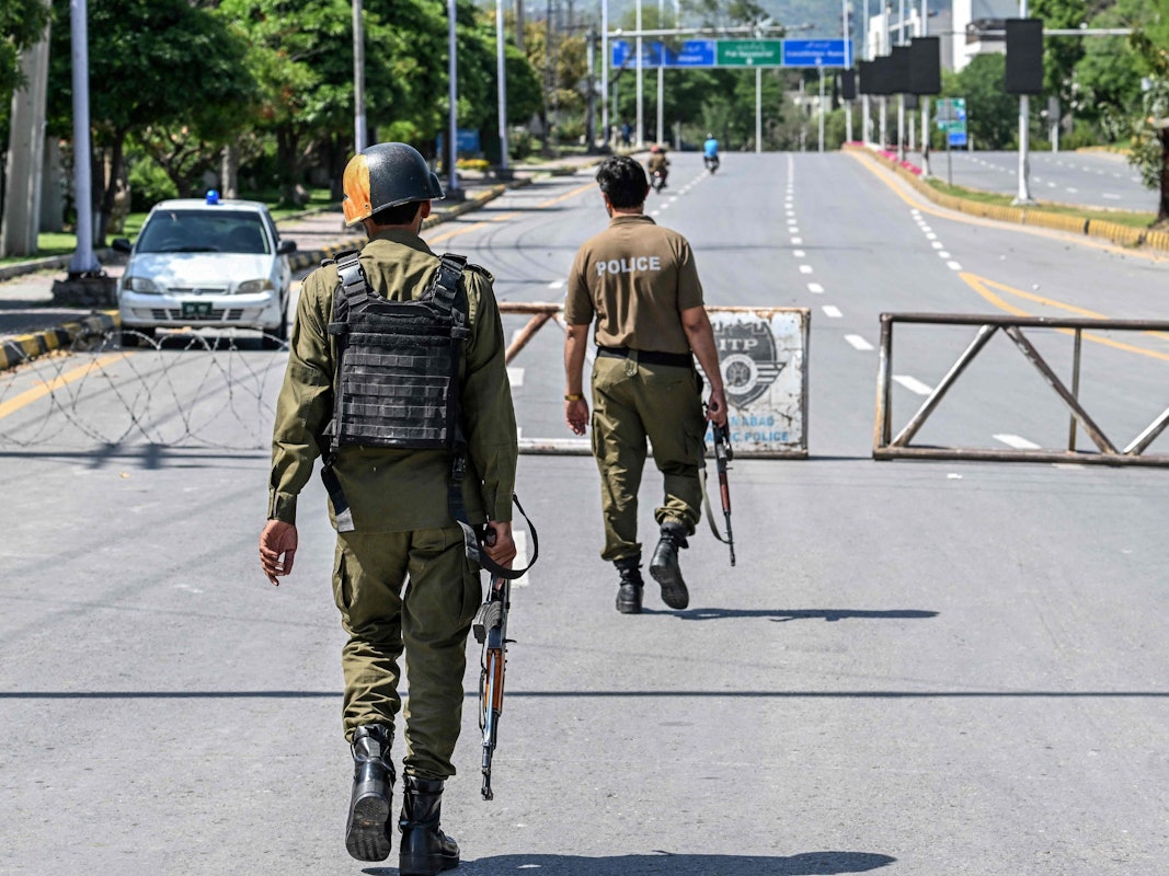 Police personnel keep watch at a closed road leading to the Serena Hotel in the Red Zone area of Islamabad on April 19, 2026. A second round of talks between the United States and Iran is expected in Islamabad this coming week. (Photo by Aamir QURESHI / AFP)