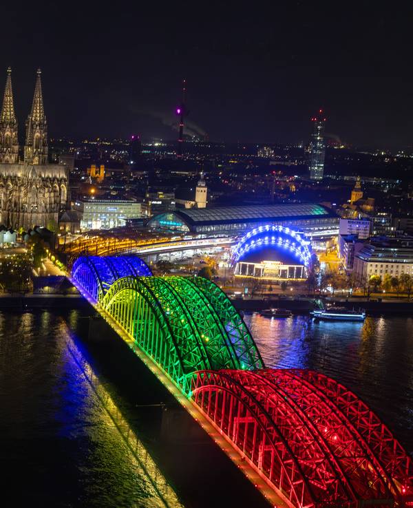 Die Bögen der Hohenzollernbrücke sind am Abend der Olympia-Abstimmung bunt beleuchtet wie Olympiaringe.