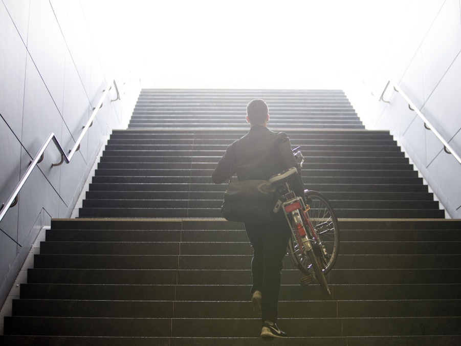 Mann trägt sein Fahrrad eine Treppe hinauf