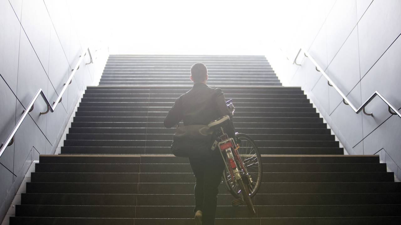 Mann trägt sein Fahrrad eine Treppe hinauf