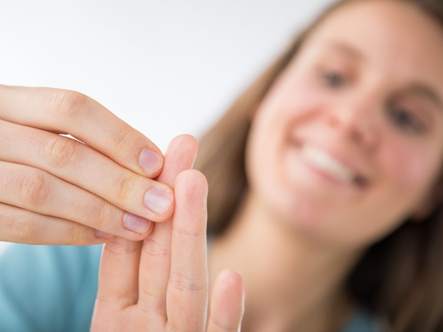 Eine Frau betrachtet ihre Fingernägel