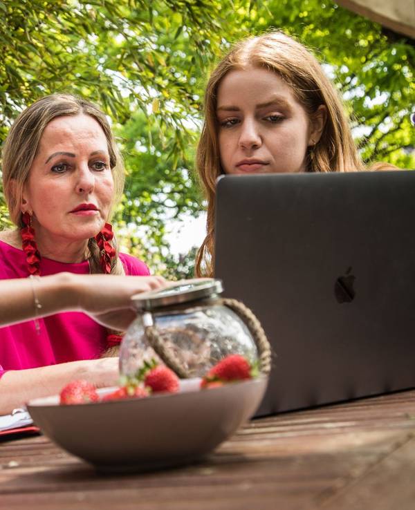 Mutter und ihre Töchter sitzen vor einem Laptop