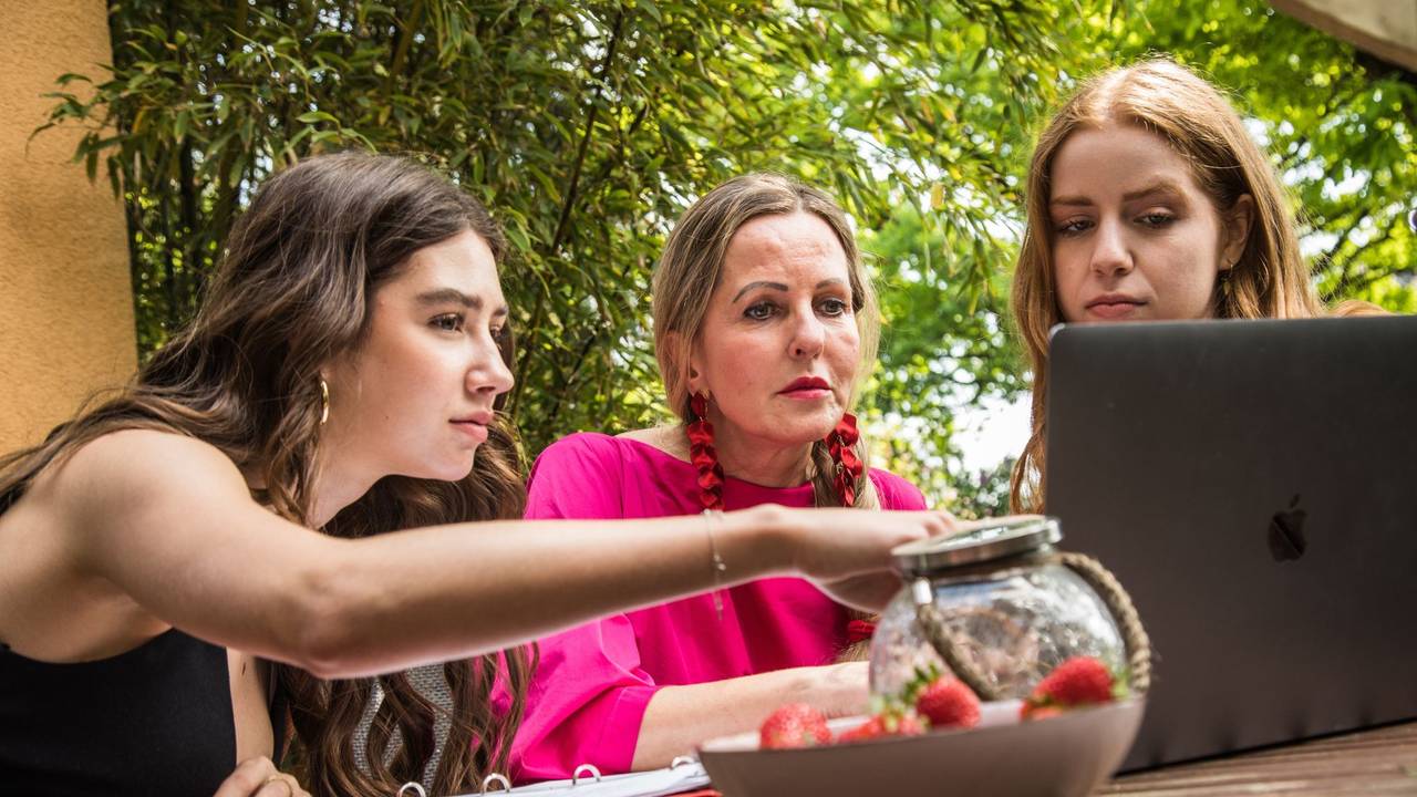 Mutter und ihre Töchter sitzen vor einem Laptop