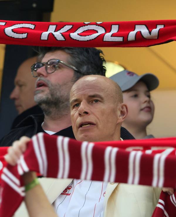 Jörn Stobbe hält bei der Hymne des 1. FC Köln seinen Schal hoch.