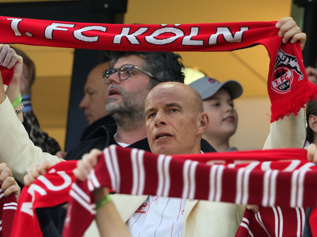 Jörn Stobbe hält bei der Hymne des 1. FC Köln seinen Schal hoch.