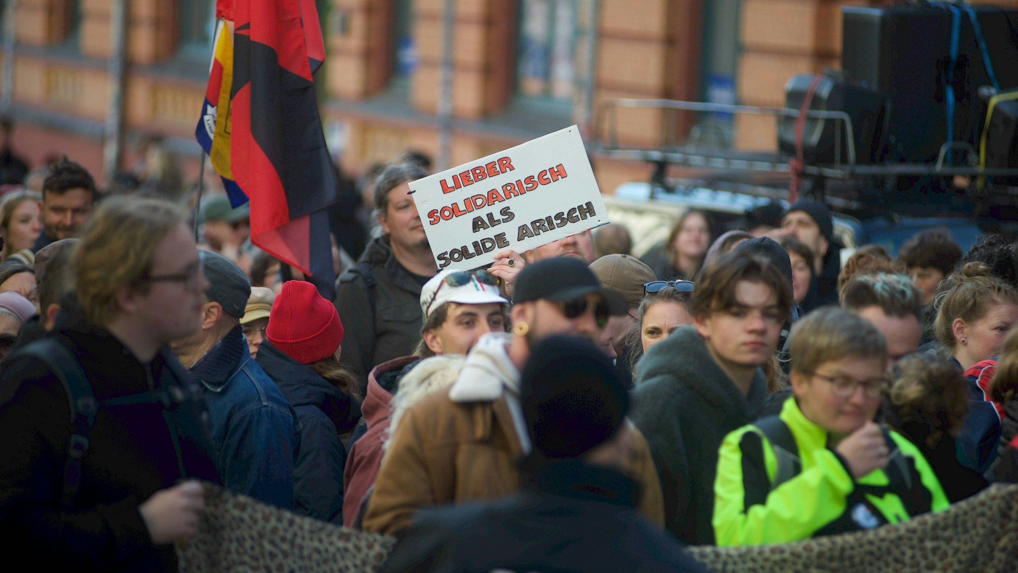Menschenmenge bei Demonstration mit Plakat und Polizist