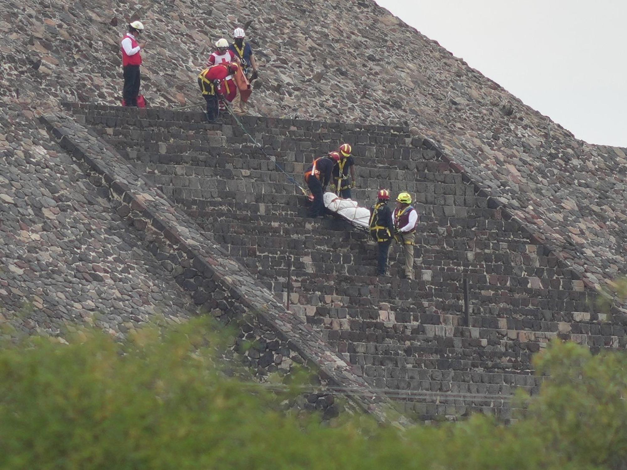 Gerichtsmediziner tragen die Leiche eines Opfers eine Pyramide hinunter.