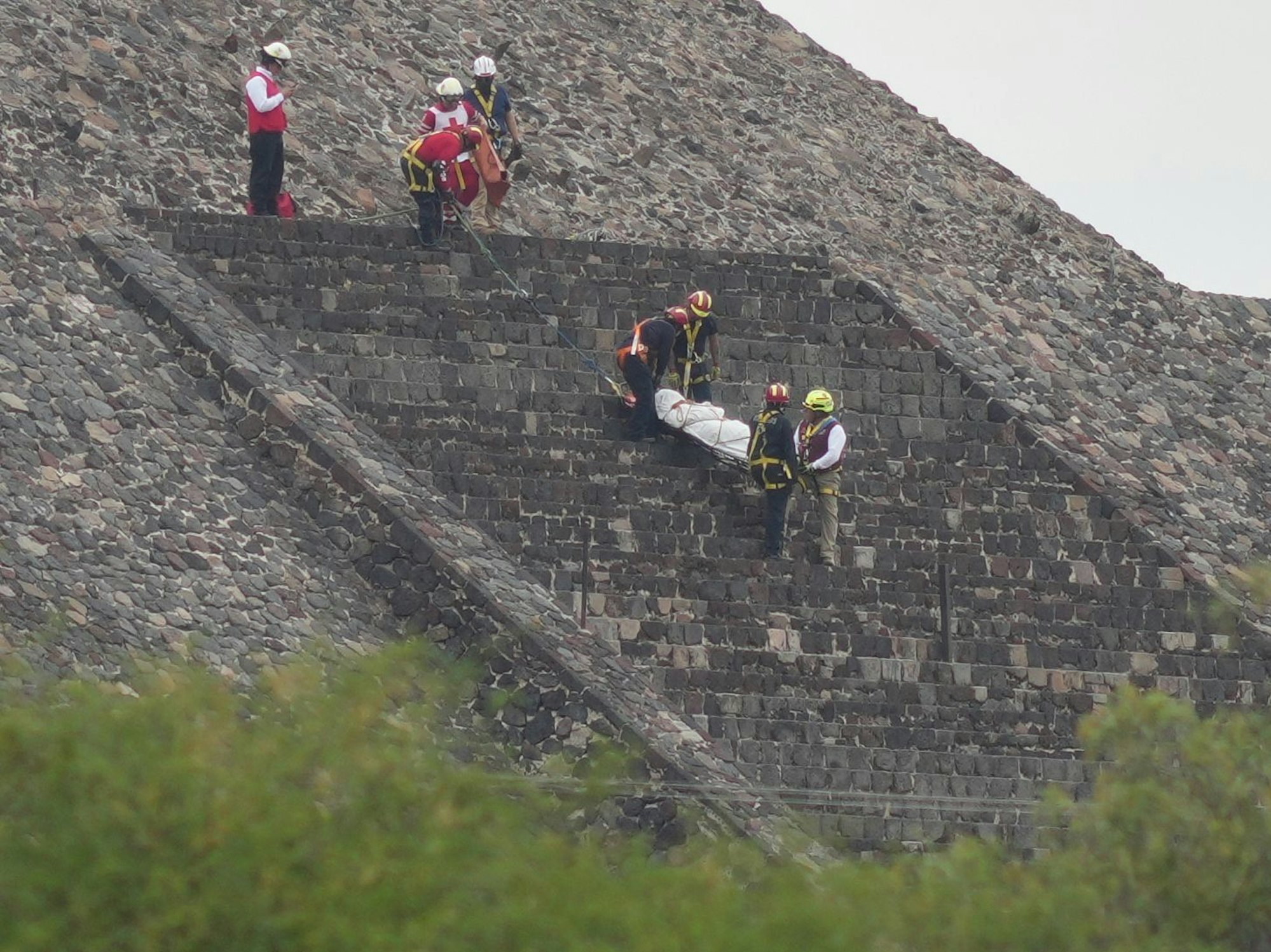 Gerichtsmediziner tragen die Leiche eines Opfers eine Pyramide hinunter.
