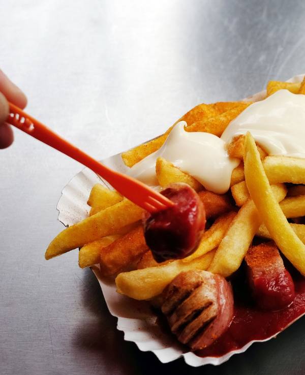 Eine Currywurst mit Pommes und Mayo