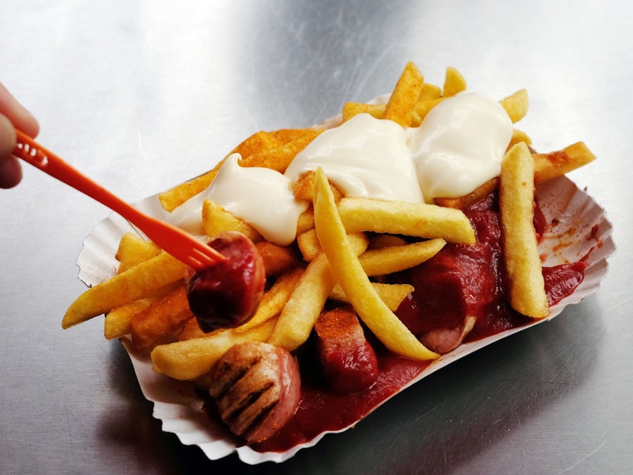 Eine Currywurst mit Pommes und Mayo