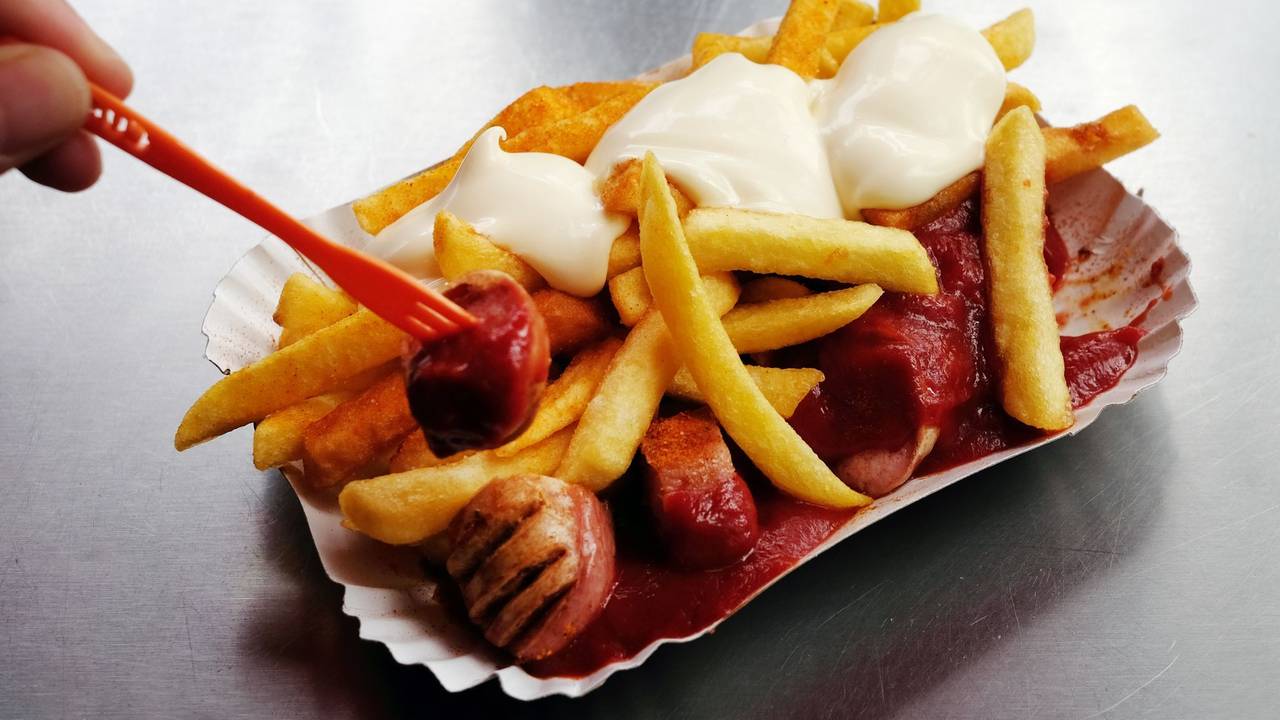 Eine Currywurst mit Pommes und Mayo