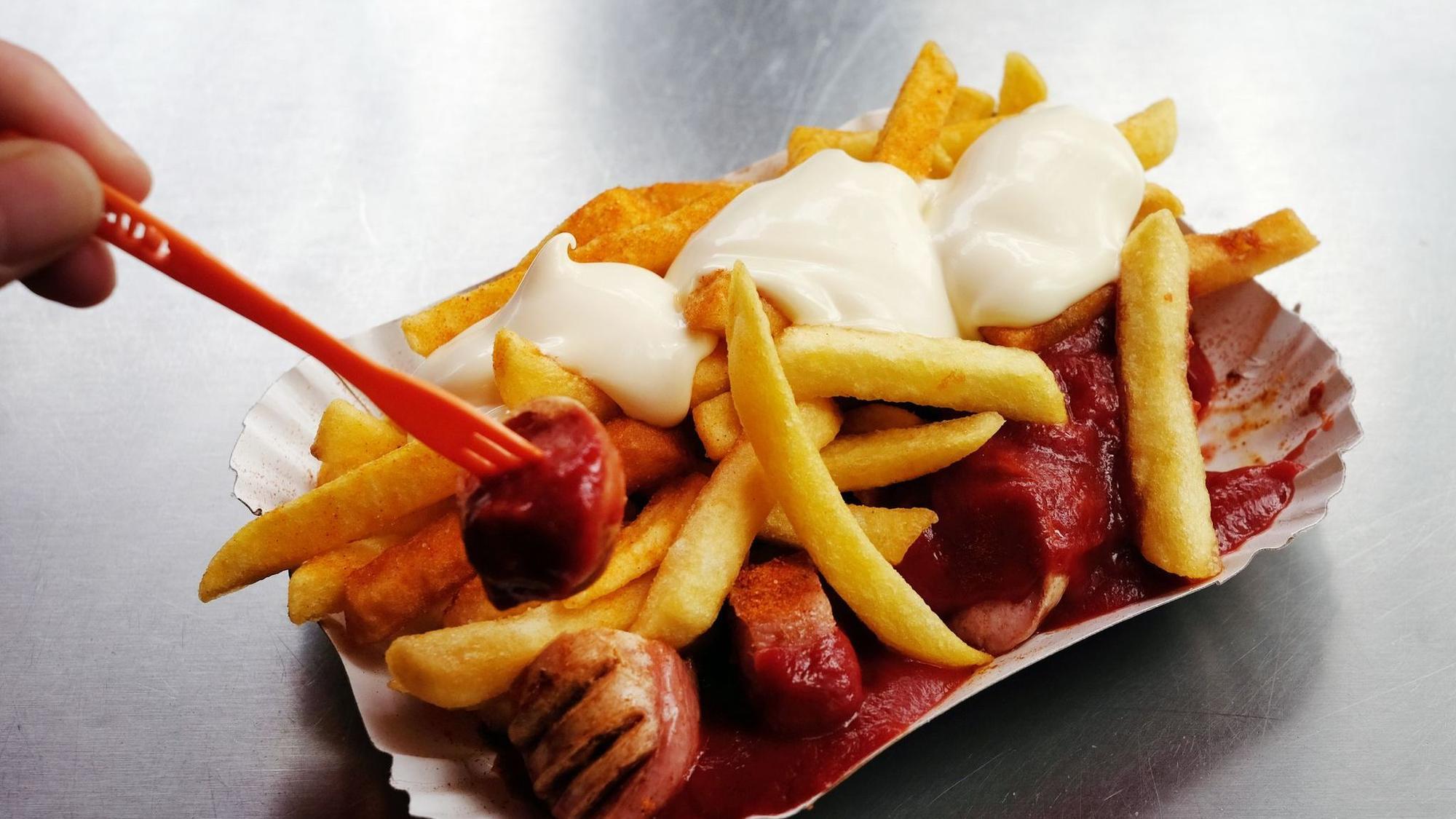 Eine Currywurst mit Pommes und Mayo