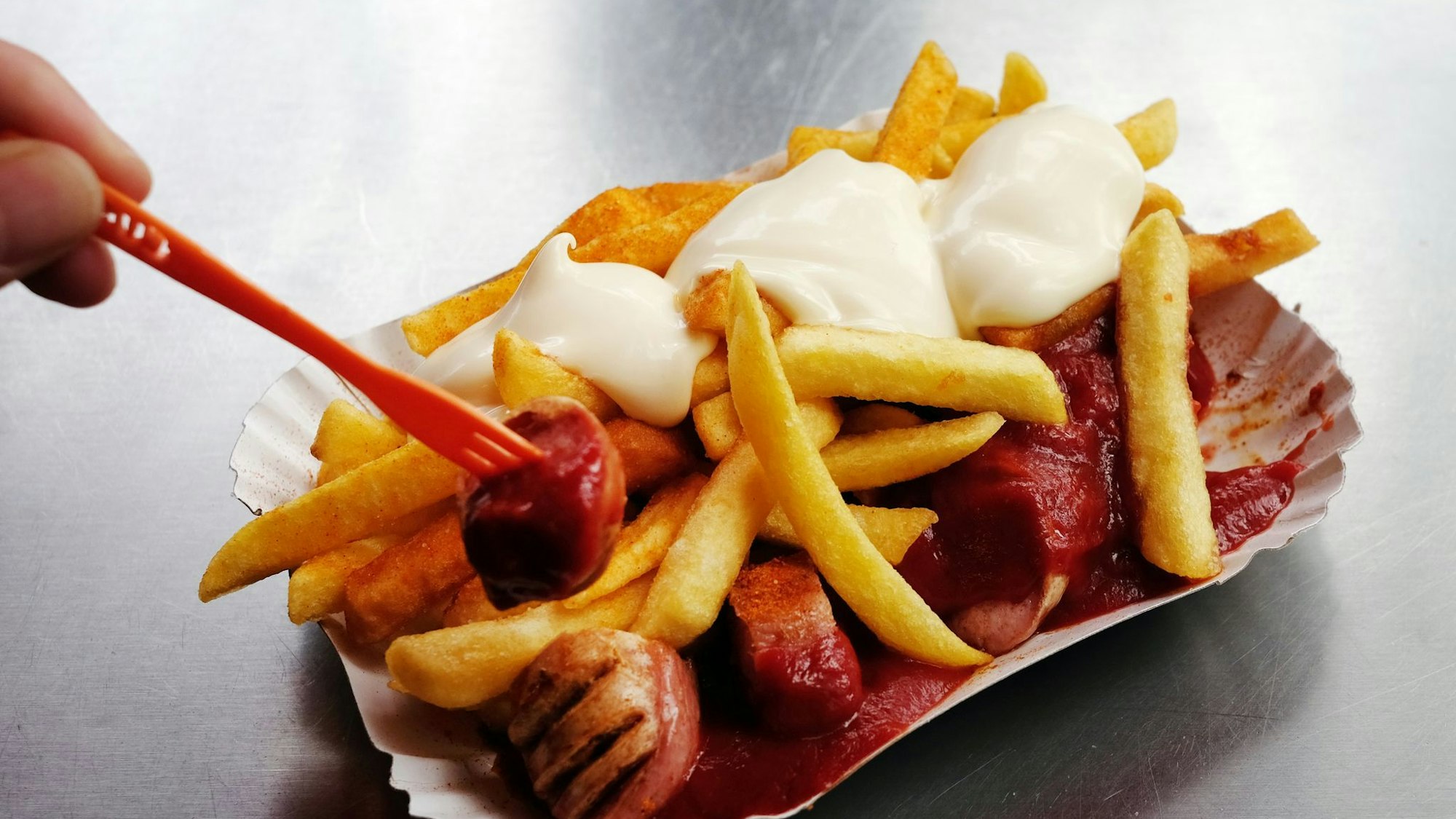 Eine Currywurst mit Pommes und Mayo