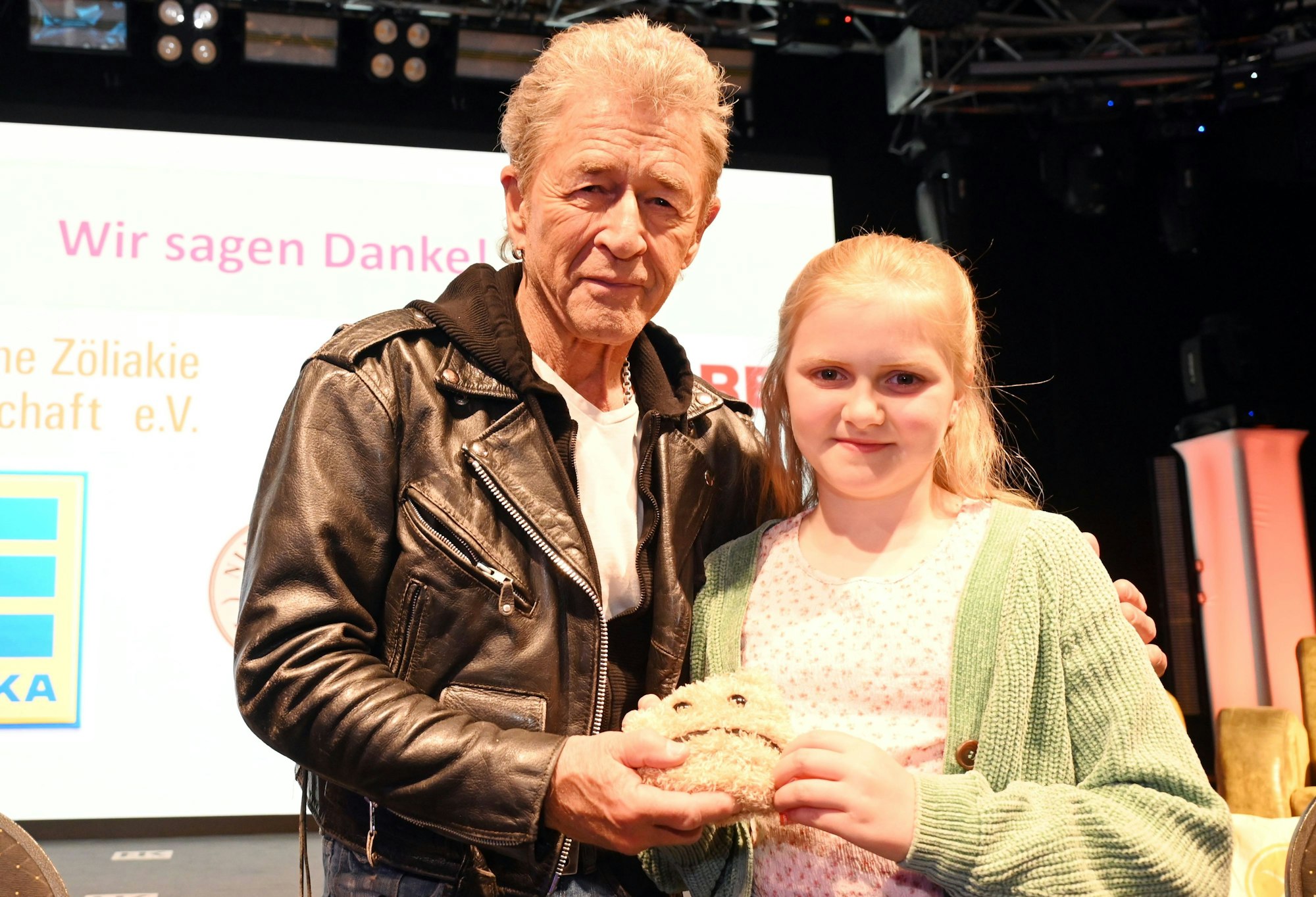 Peter Maffay steht neben einem Mädchen, sie halten ein Plüschtier in der Hand