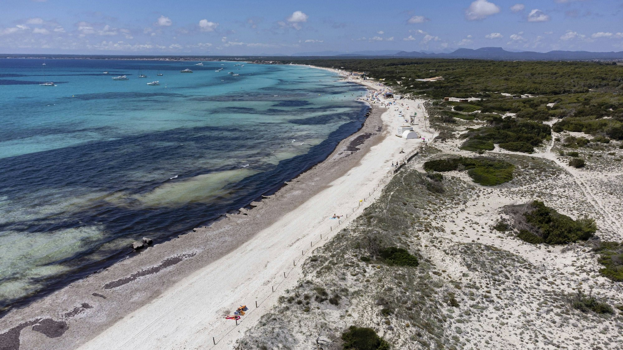 Küstenlandschaft mit Sandstrand, Meer, Booten und Vegetation