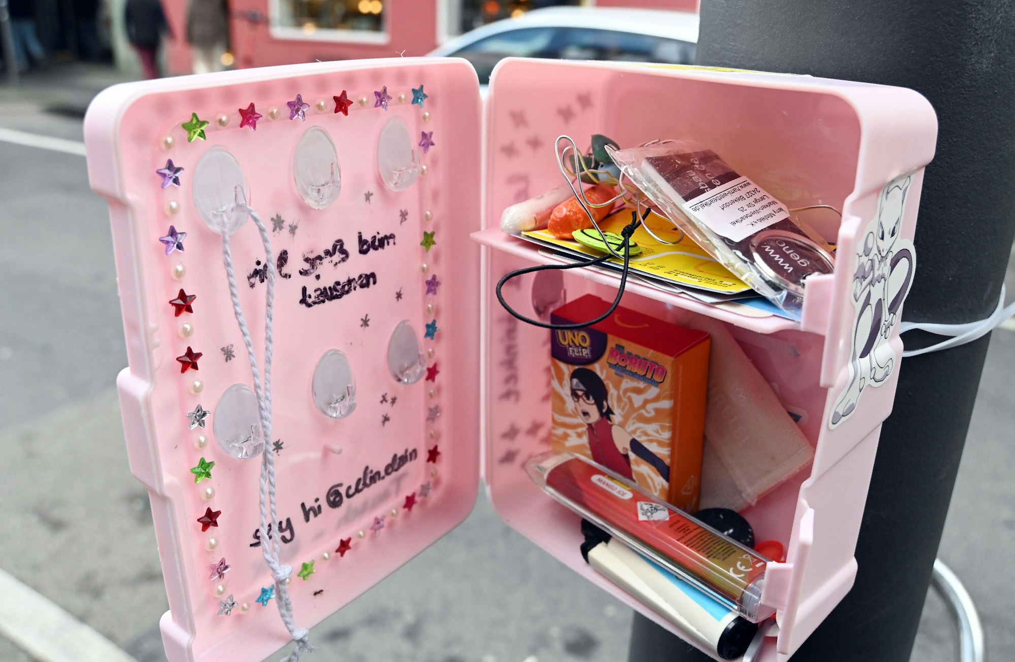 Eine kleine Box ist an einem Pfahl befestigt, darin Krimskrams.