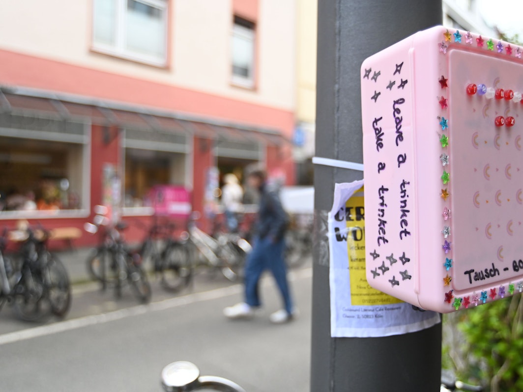 Eine bunte, mit Stickern beklebte Box hängt an einem Pfahl.