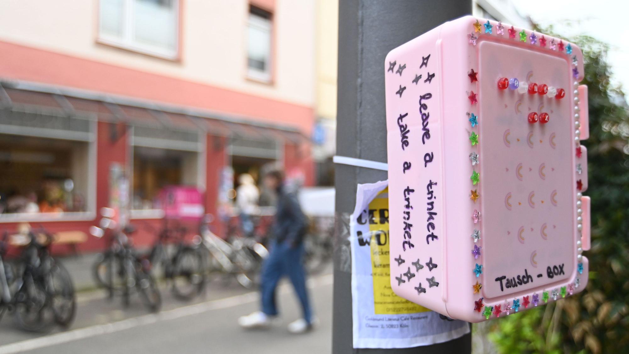 Eine bunte, mit Stickern beklebte Box hängt an einem Pfahl.
