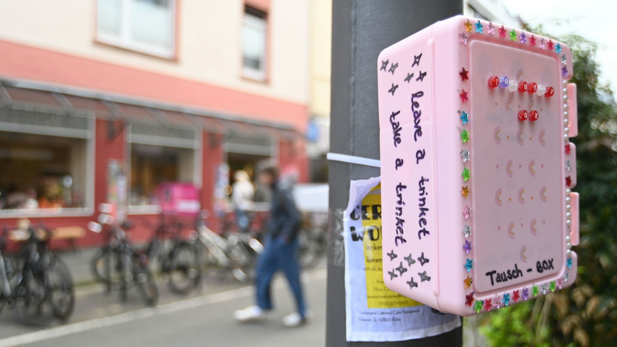 Eine bunte, mit Stickern beklebte Box hängt an einem Pfahl.