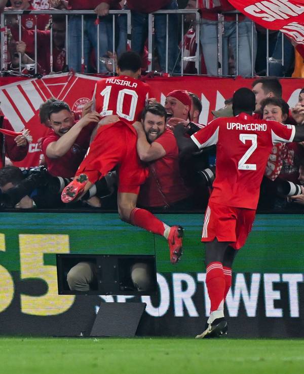 Jamal Musiala (l.) und Dayot Upamecano jubeln beim Spiel gegen Real Madrid mit den Fans.