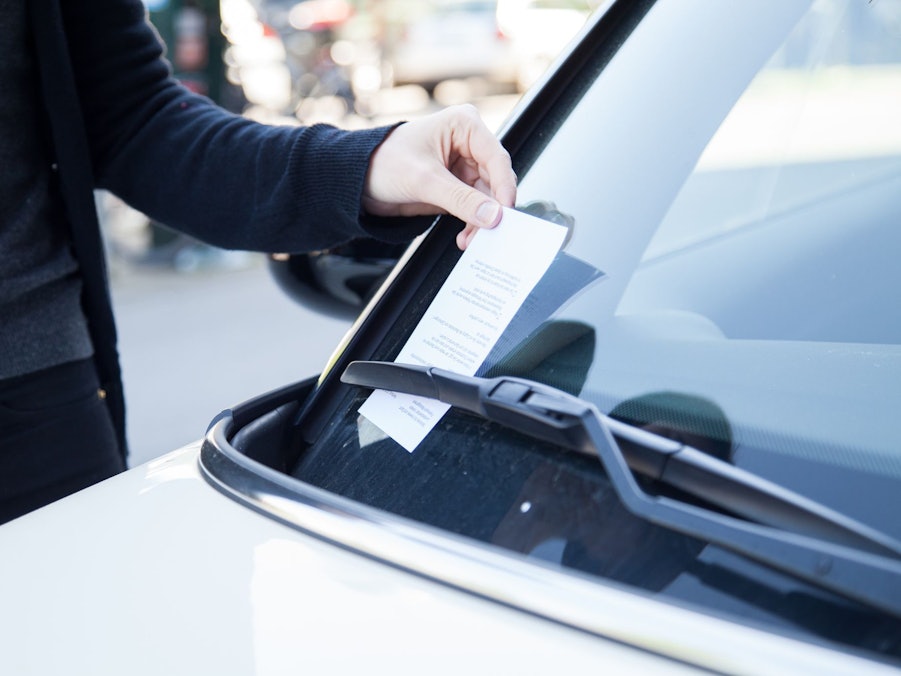 Frau greift nach einem Strafzettel an ihrem Auto