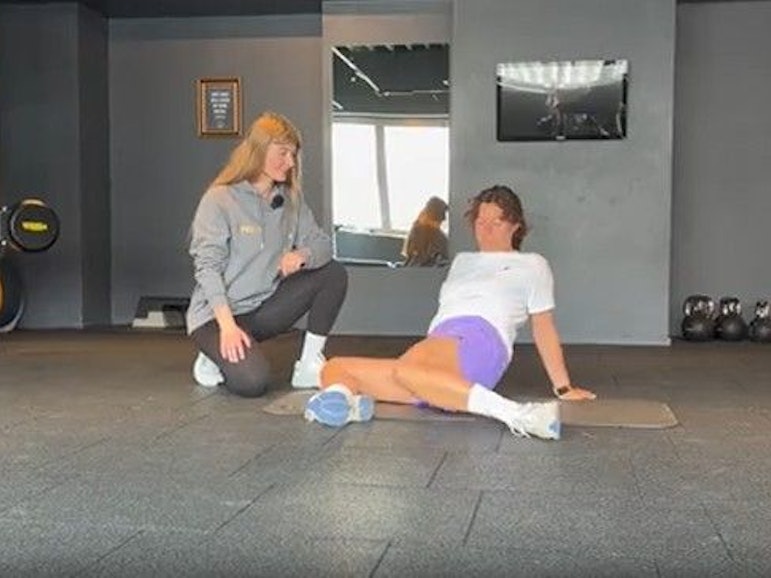 Eine Fitnesstrainerin erklärt einer Frau eine Sportübung.